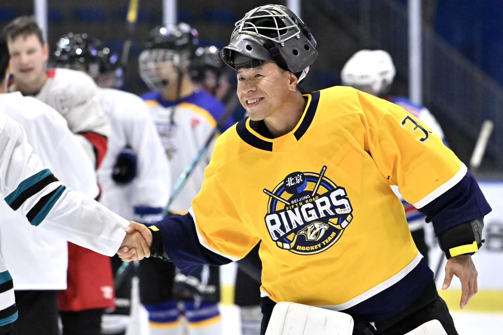 Smiling goalie in a yellow Ringers jersey greeting another player after the game