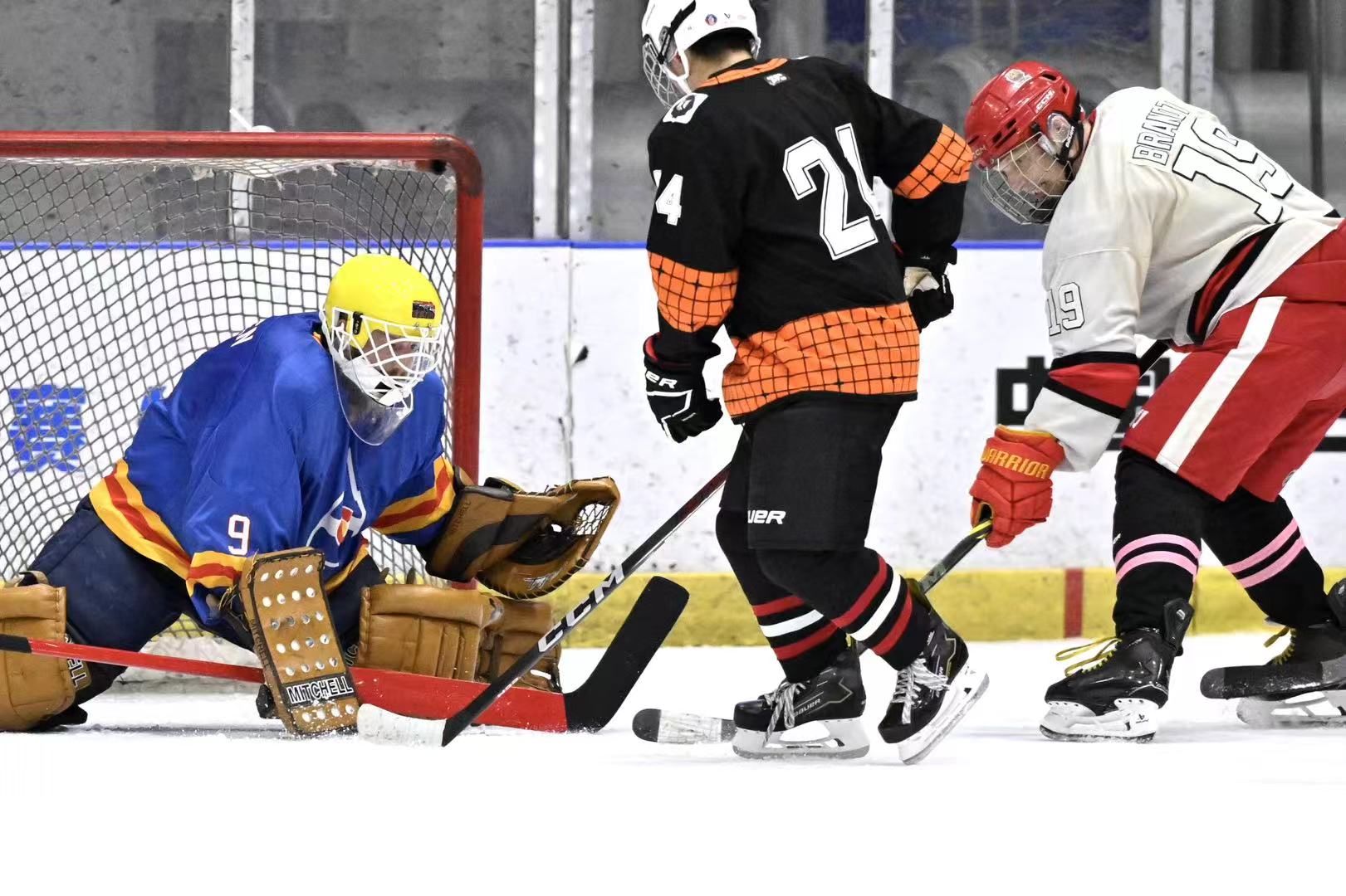 Goalie in blue gear defending the net during a crowded scoring chance