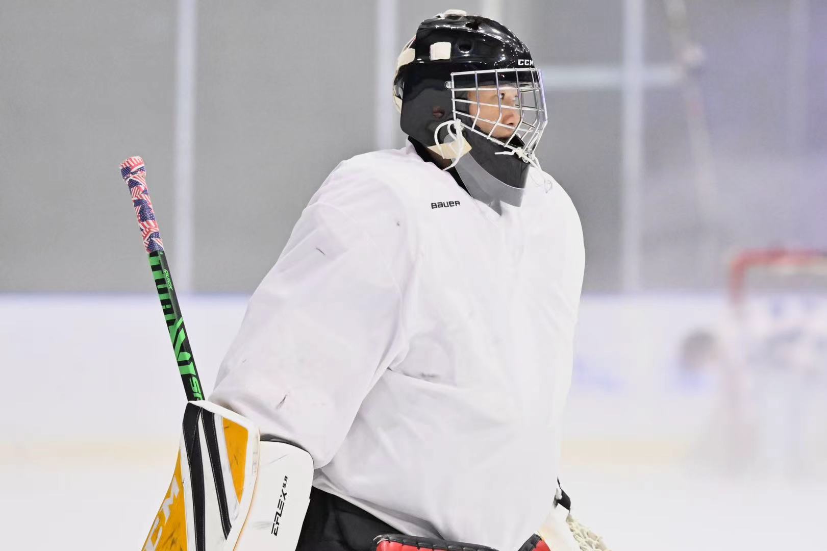 Goalie in white practice gear watching the play